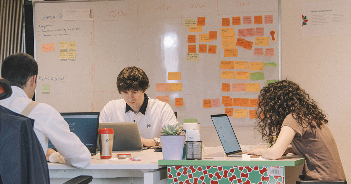 A group of people practicing agile project management at a desk.