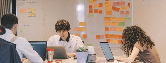 A group of people practicing agile project management at a desk.