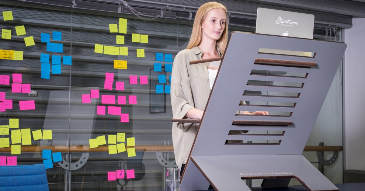 a woman standing in front of a desk with sticky notes on it.