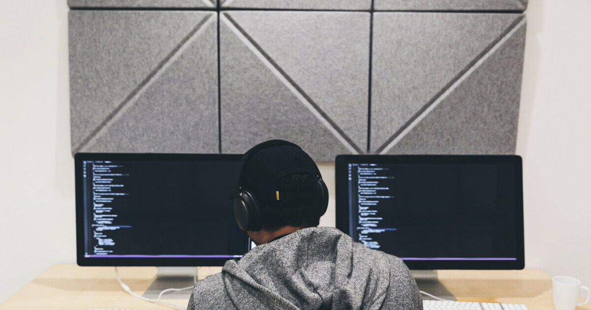 Focused programmer working diligently on coding project at a computer workstation.